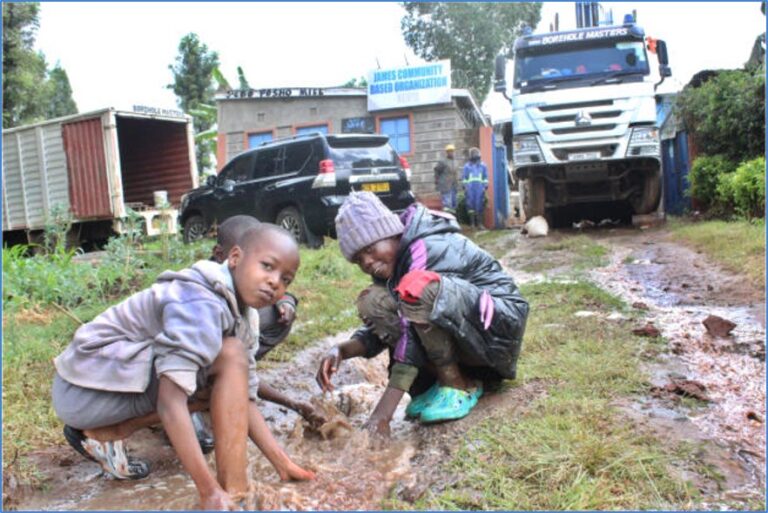 Community members gather as work on the water point continues.