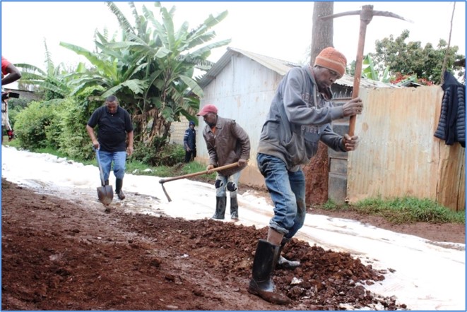 Digging trenches to carry piped water across the settlement.