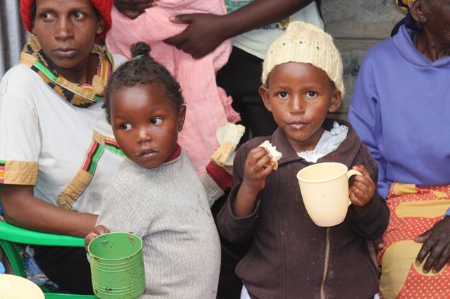 Little ones share a warm drink at a gathering.